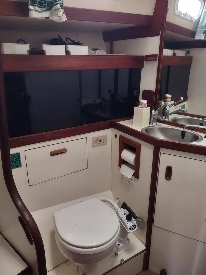 Slide: The Image of 1983 Sabre 38 yacht bathroom with sink, toilet, and storage shelves. - 12