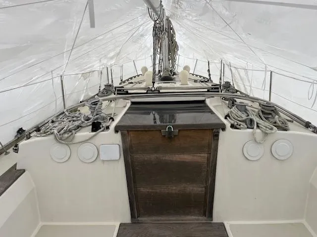 Slide: The Image of 1983 Sabre 38 sailboat deck under cover, featuring rigging and wooden hatch. - 16