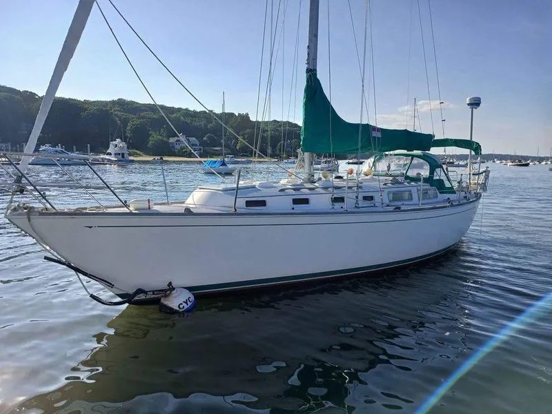 Slide: The Image of 1983 Sabre 38 sailboat on calm water, green sail cover, scenic background. - 4