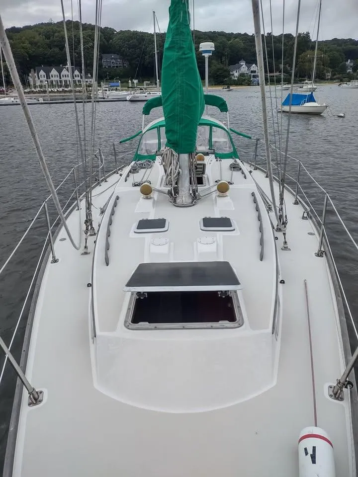 Slide: The Image of 1983 Sabre 38 sailboat deck with green sail cover, docked in a scenic marina. - 6