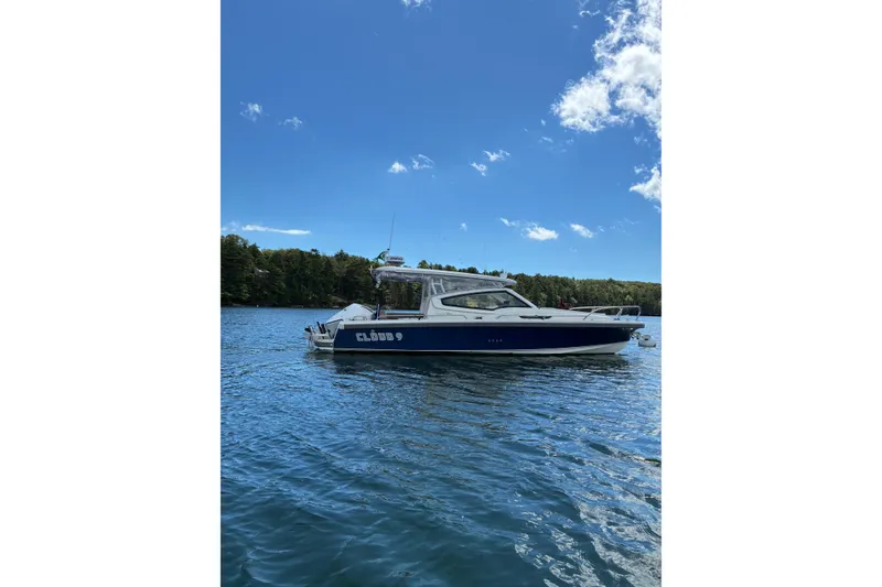 Slide: The Image of 2023 Nimbus W9 boat on a serene lake under a clear blue sky. - 11