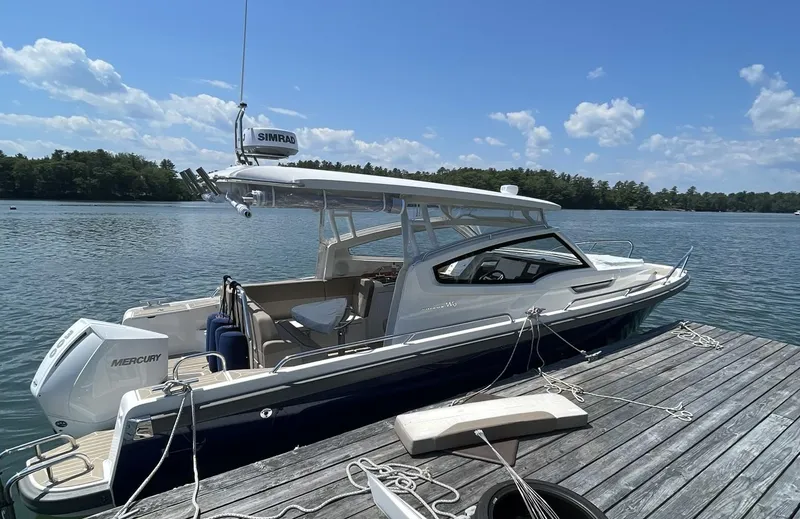 Slide: The Image of Nimbus W9 2023 boat docked on a serene lake under a partly cloudy sky. - 2