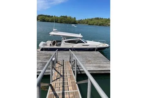 Slide: The Image of 2023 Nimbus W9 boat docked on a serene lake with lush green surroundings. - 4