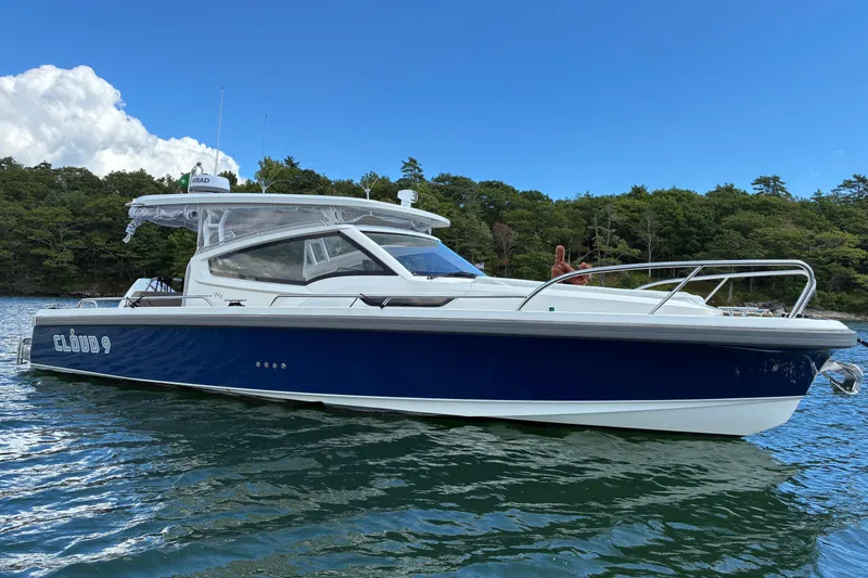 Slide: The Image of 2023 Nimbus W9 boat on water, blue and white design, lush green background. - 12