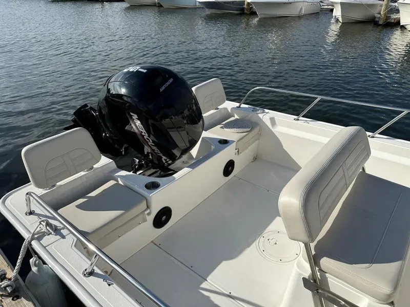 Slide: The Image of 2024 Boston Whaler 190 Montauk boat interior with Mercury outboard motor, docked on calm water. - 3