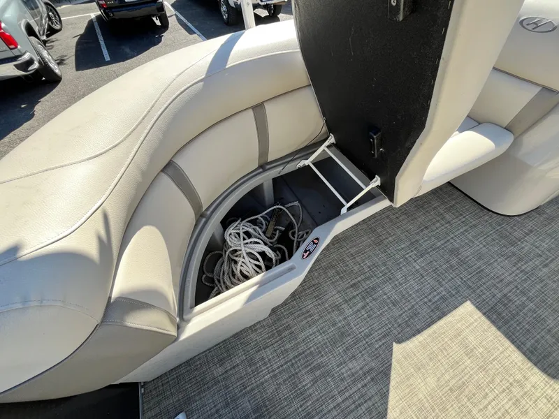 Slide: The Image of 2020 Harris FloteBote Cruiser 230 interior storage compartment with rope, beige seating, and carpeted floor. - 14
