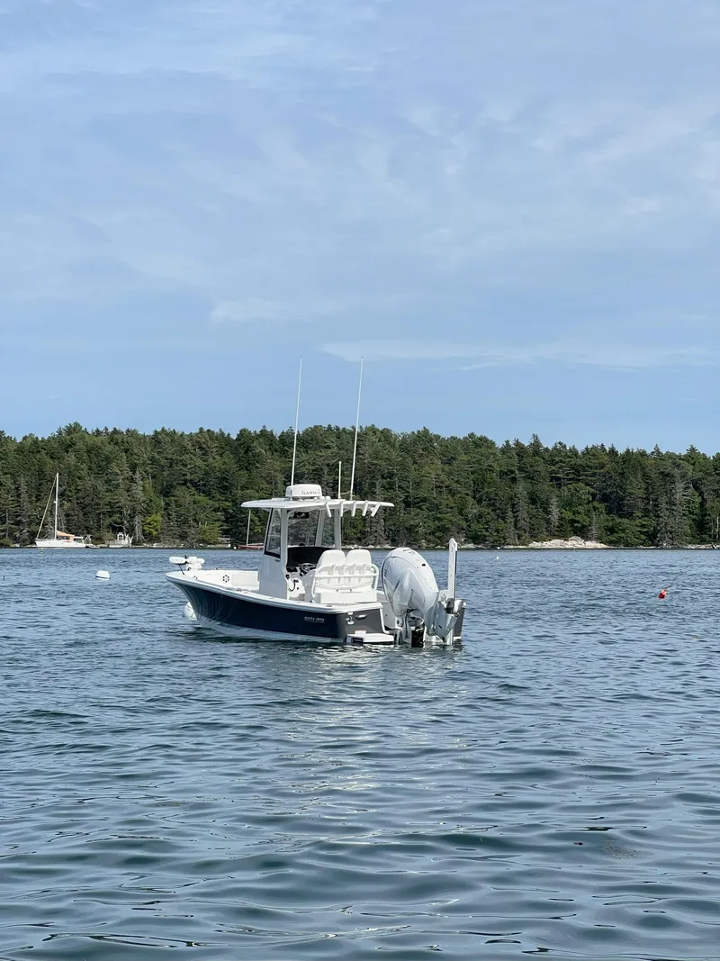 Slide: The Image of 2021 Regulator 26XO boat on calm water with forested shoreline in background. - 11