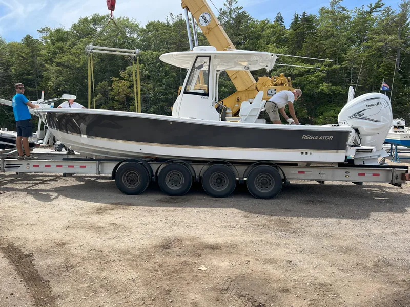 Slide: The Image of 2021 Regulator 26XO boat on trailer, surrounded by trees and people. - 14
