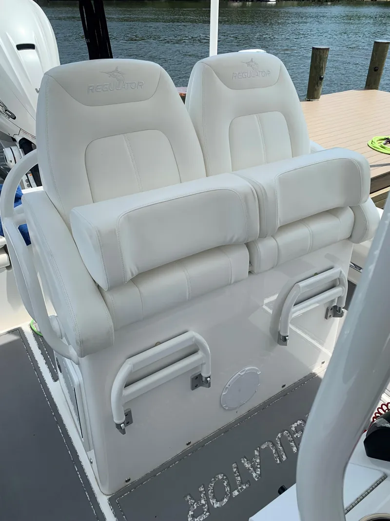 Slide: The Image of 2021 Regulator 26XO boat with white cushioned seats, dockside view. - 3