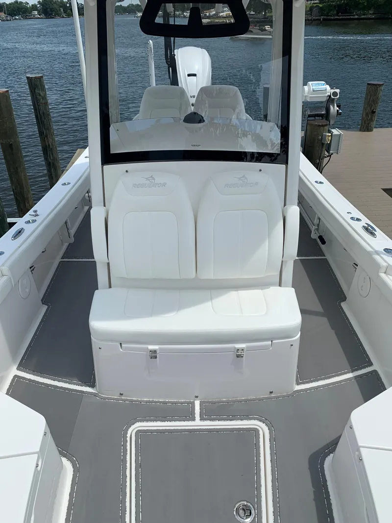 Slide: The Image of 2021 Regulator 26XO boat interior with seating, docked by the water. - 6