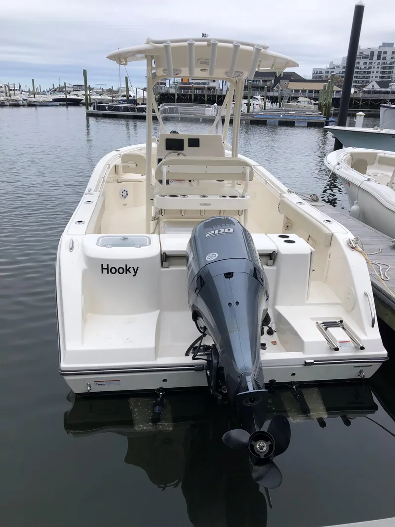Slide: The Image of 2023 Cobia 220 CC boat docked, featuring a powerful outboard motor. - 2
