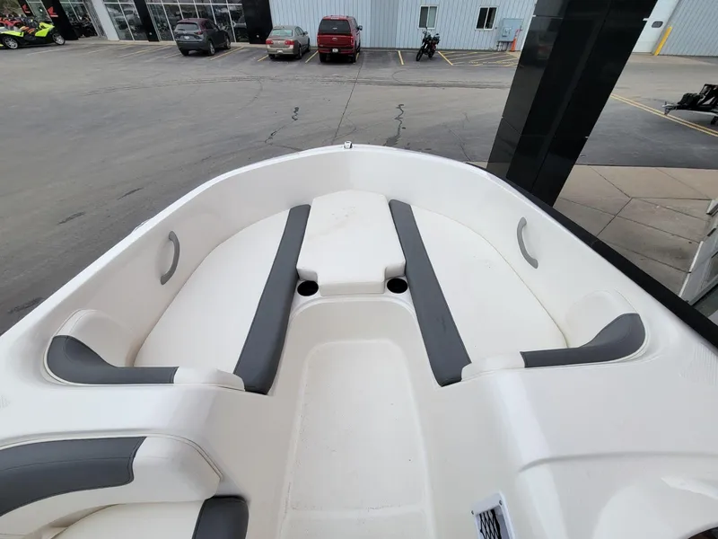 Slide: The Image of 2025 Bayliner Element E18 boat interior with white and gray seating, parked outdoors. - 17