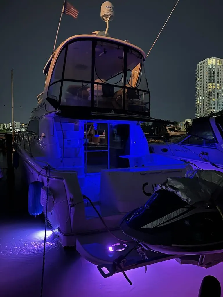 Slide: The Image of 2000 Sea Ray 480 Sedan Bridge yacht illuminated at night in a marina. - 12