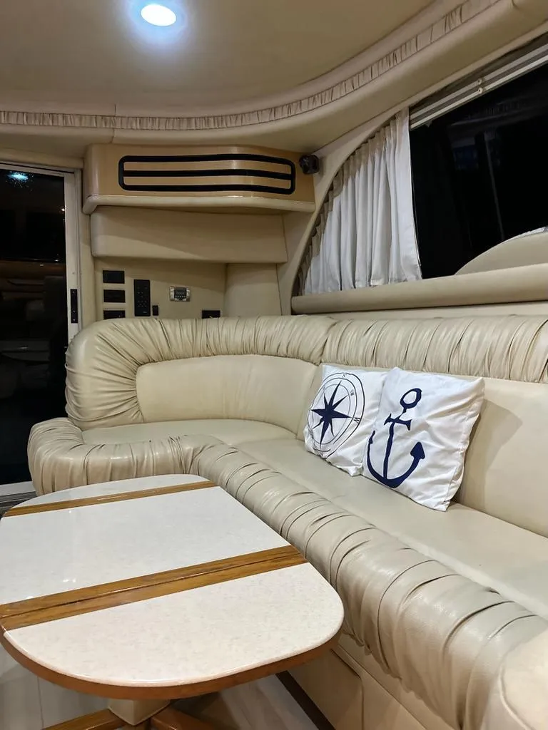 Slide: The Image of Luxurious interior of 2000 Sea Ray 480 Sedan Bridge with plush seating and nautical-themed pillows. - 9