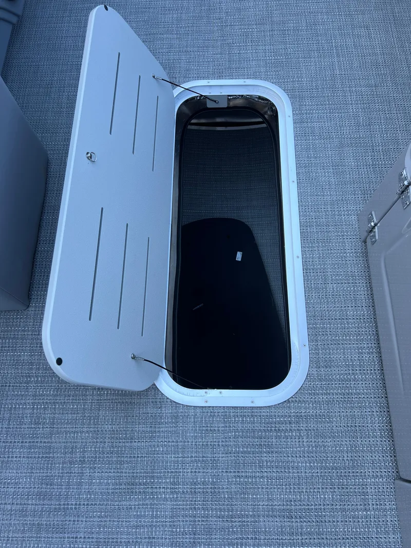 Slide: The Image of 2025 Bentley Pontoons Legacy 243 Navigator storage compartment with open hatch on textured flooring. - 21