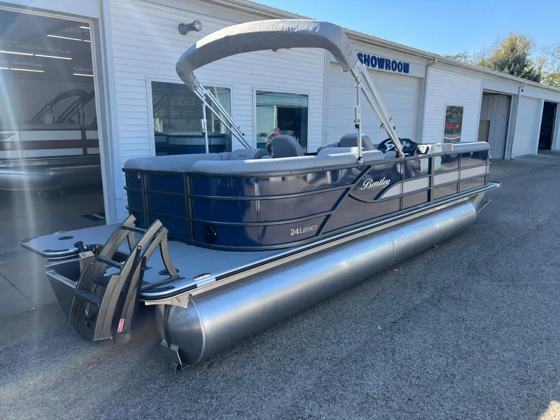 Slide: The Image of 2025 Bentley Pontoons Legacy 243 Navigator in showroom, sleek design, blue exterior. - 7