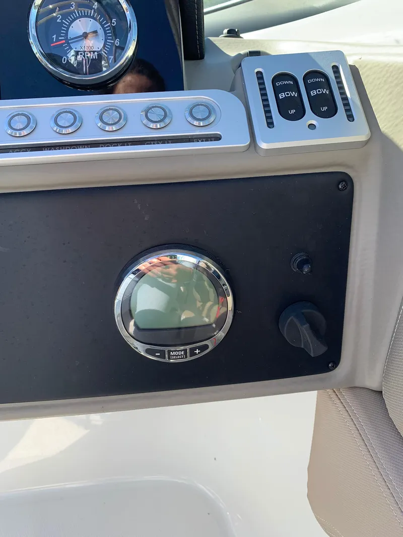 Slide: The Image of Dashboard controls of 2023 Crownline E235XS boat, featuring RPM gauge and trim switches. - 11