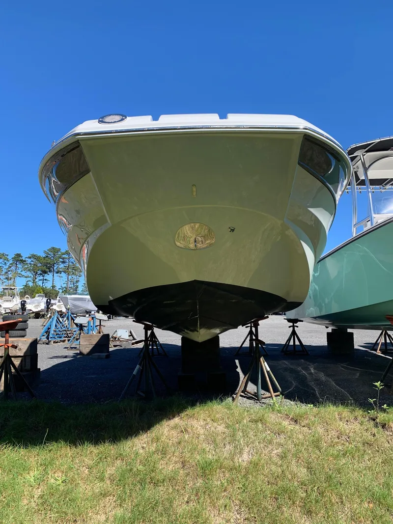 Slide: The Image of 2023 Crownline E235XS boat on stands, viewed from the front, under clear blue sky. - 2