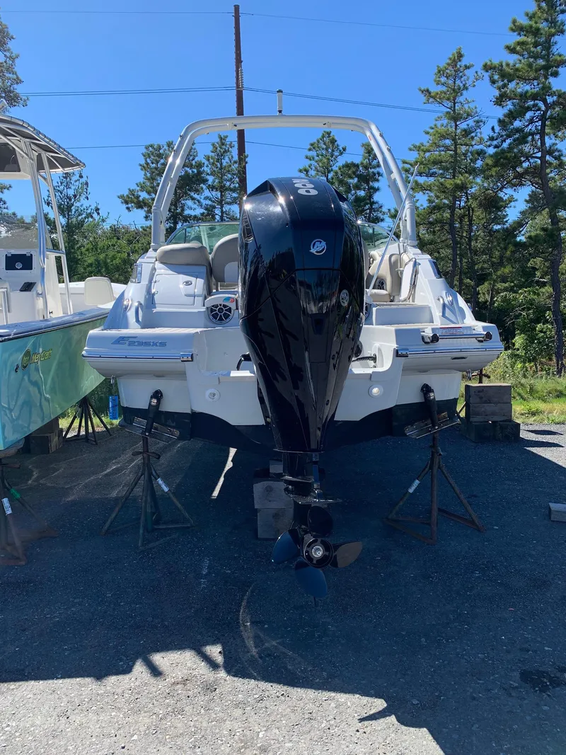 Slide: The Image of 2023 Crownline E235XS boat with outboard motor, parked on stands outdoors. - 3