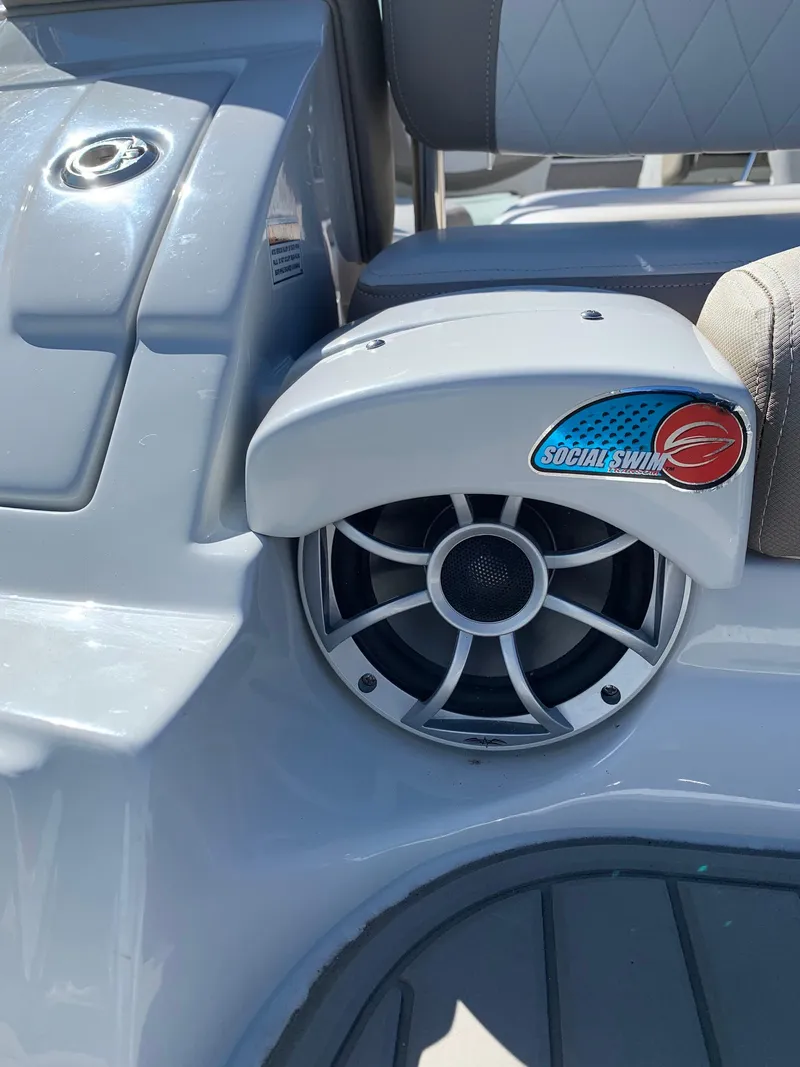 Slide: The Image of 2023 Crownline E235XS boat speaker with "Social Swim" logo on gray interior. - 4