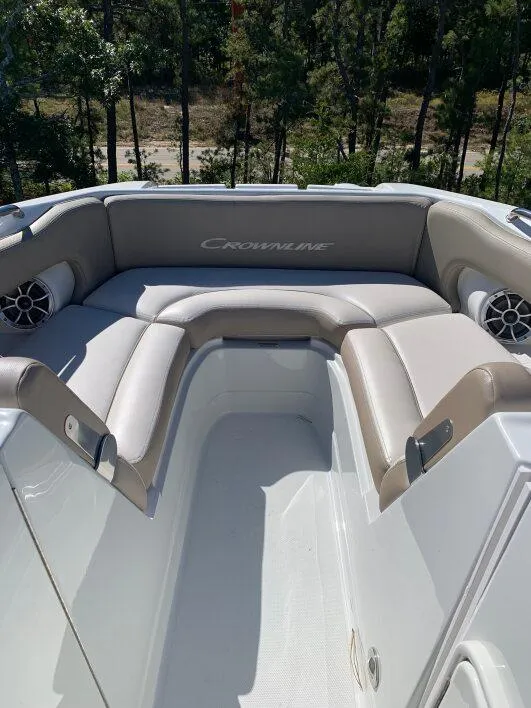 Slide: The Image of 2022 Crownline E235XS boat interior with cushioned seating and speakers, surrounded by trees. - 3