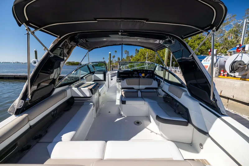 Slide: The Image of 2017 Formula 330 Crossover Bowrider with spacious seating and canopy, docked by the water. - 18