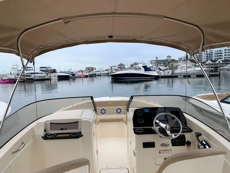 Slide: The Image of 2023 Scout 215 Dorado boat interior at marina, showcasing helm and seating area. - 2