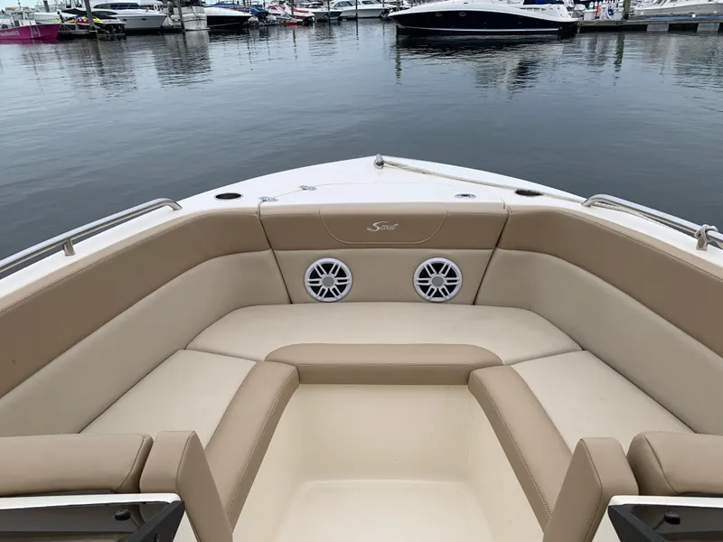 Slide: The Image of 2023 Scout 215 Dorado boat interior with beige seating at a marina. - 3