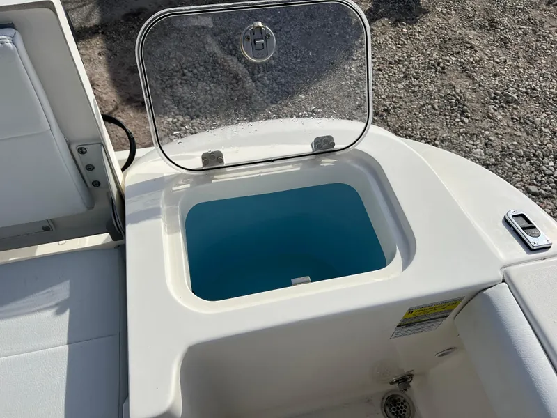 Slide: The Image of 2023 Cobia 220 Dual Console boat with open storage compartment. - 12