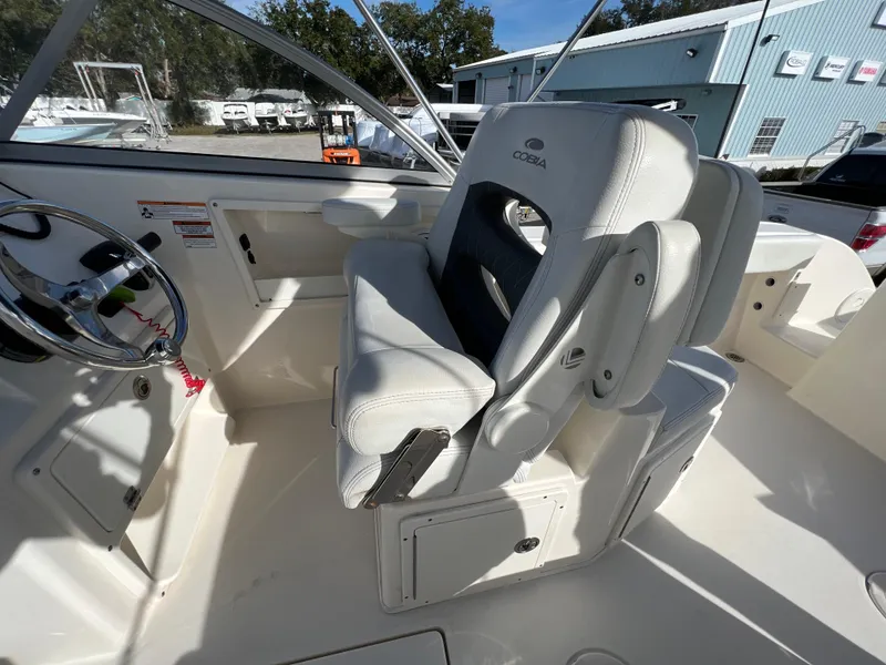 Slide: The Image of 2023 Cobia 220 Dual Console boat interior with white seating and steering wheel. - 13