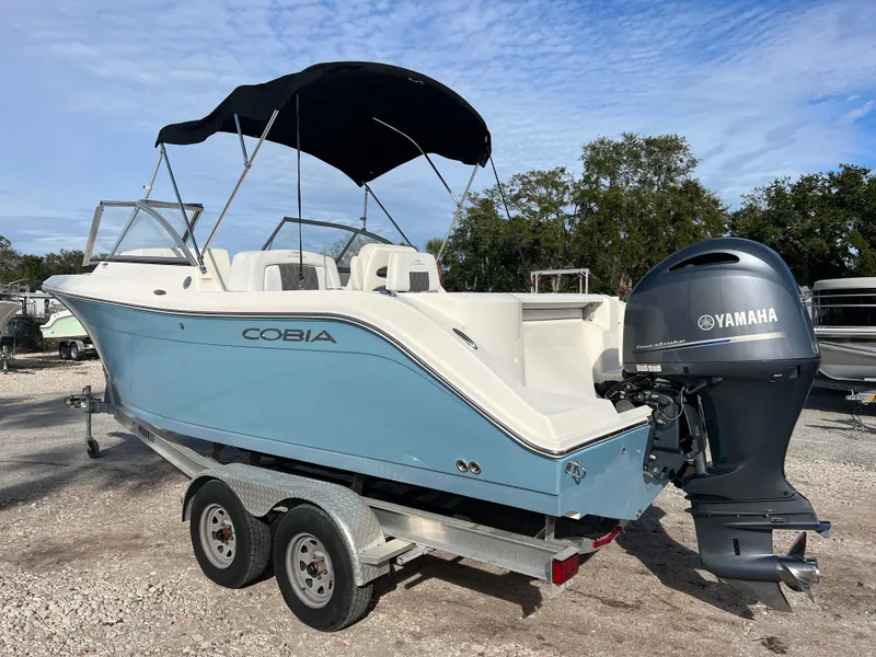 Slide: The Image of 2023 Cobia 220 Dual Console boat with Yamaha engine on trailer, blue hull, black canopy. - 5