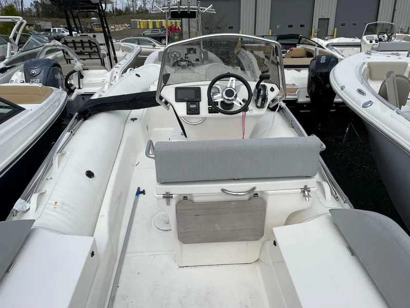 Slide: The Image of 2023 Zodiac N-ZO 680 boat interior with steering wheel and seating, docked among other boats. - 4