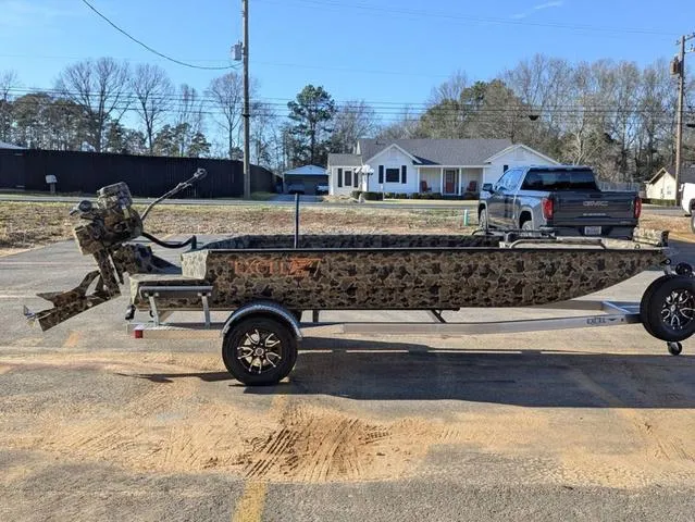 Slide: The Image of 2025 Excel 1854 Shallow Water F4 boat on trailer, camo design, parked outdoors. - 7