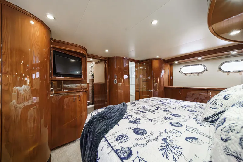 Slide: The Image of Luxurious 2004 Marquis 59 yacht bedroom with elegant wood finishes and nautical-themed bedding. - 24
