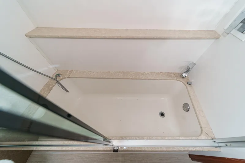 Slide: The Image of Bathtub in a 2004 Marquis 59 yacht, featuring a glass door and marble trim. - 30