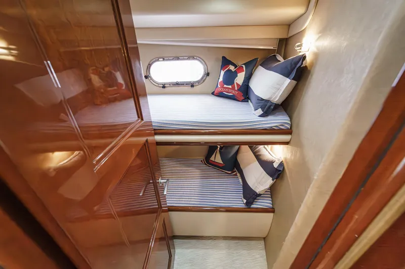 Slide: The Image of 2004 Marquis 59 yacht cabin with bunk beds and nautical-themed pillows. - 36