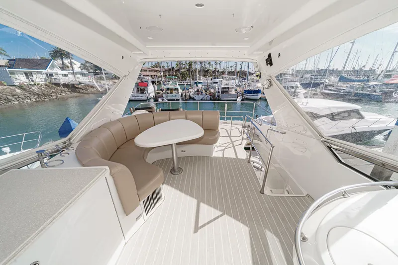 Slide: The Image of Luxurious 2004 Marquis 59 yacht interior with curved seating and table, docked at a marina. - 45