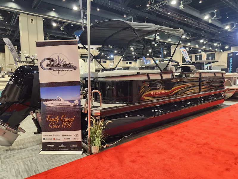 Slide: The Image of 2025 Regency 250 LE3 pontoon boat displayed indoors on red carpet. - 1