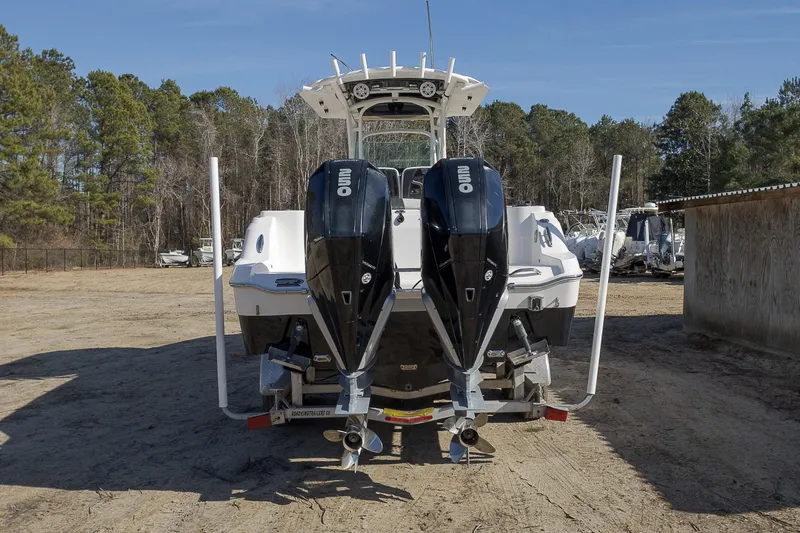 Slide: The Image of 2019 Wellcraft 262 Fisherman boat with dual outboard engines, parked on sandy ground. - 2