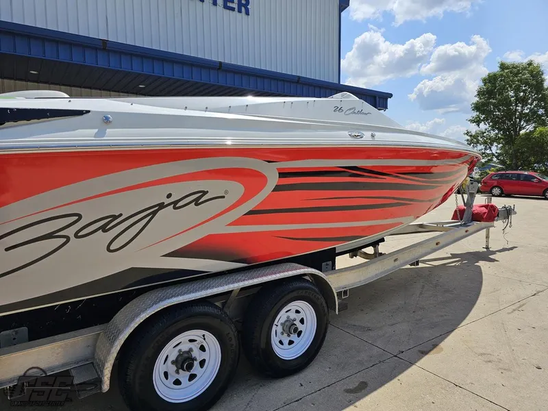 Slide: The Image of 2007 Baja 26 Outlaw boat on trailer, vibrant red and white design, parked outdoors. - 14