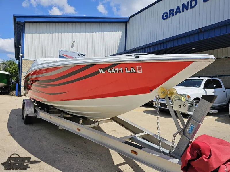 Slide: The Image of 2007 Baja 26 Outlaw boat with red and black design on a trailer outside a building. - 17