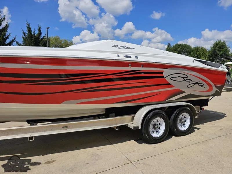 Slide: The Image of 2007 Baja 26 Outlaw speedboat with red and black graphics on a trailer under a blue sky. - 24