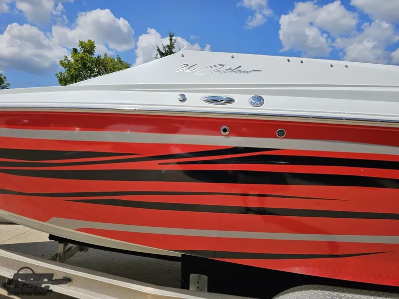 Slide: The Image of 2007 Baja 26 Outlaw boat with red and black stripes under a blue sky. - 26