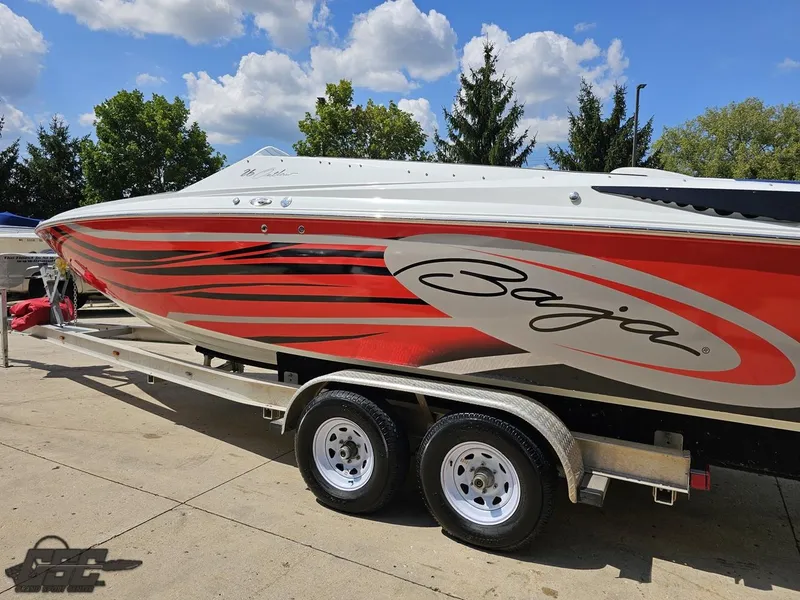 Slide: The Image of 2007 Baja 26 Outlaw boat with red and black graphics on a trailer. - 28