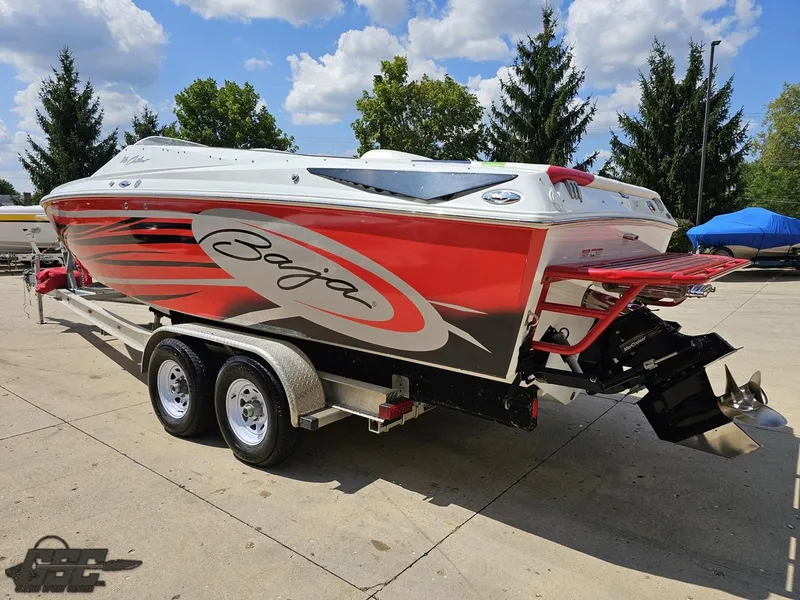 Slide: The Image of 2007 Baja 26 Outlaw boat on trailer, red and white design, parked outdoors. - 29