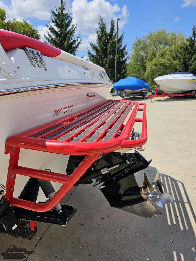 Slide: The Image of 2007 Baja 26 Outlaw boat with red swim platform, parked outdoors. - 30