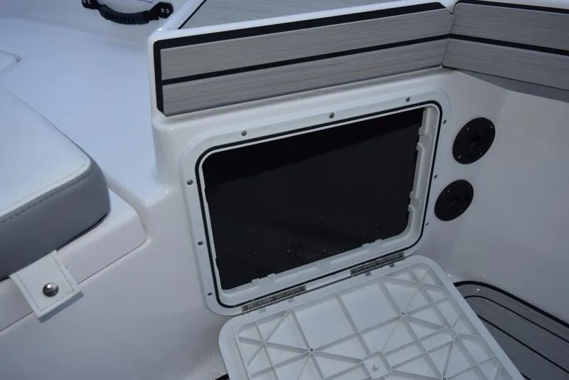 Slide: The Image of 2025 Yamaha Boats 195 FSH Sport storage compartment, open and empty, with sleek interior design. - 14