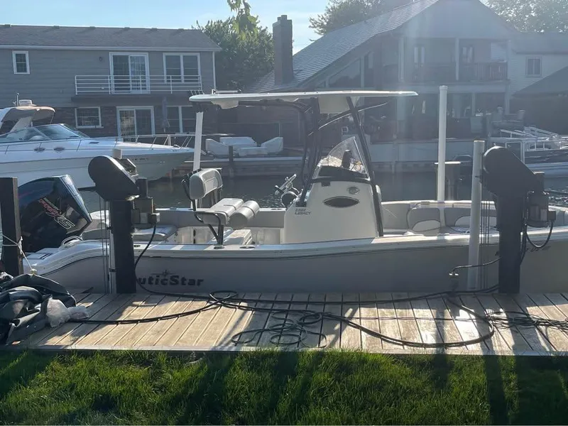 Slide: The Image of 2022 NauticStar 2302 Legacy boat docked by waterfront homes. - 10