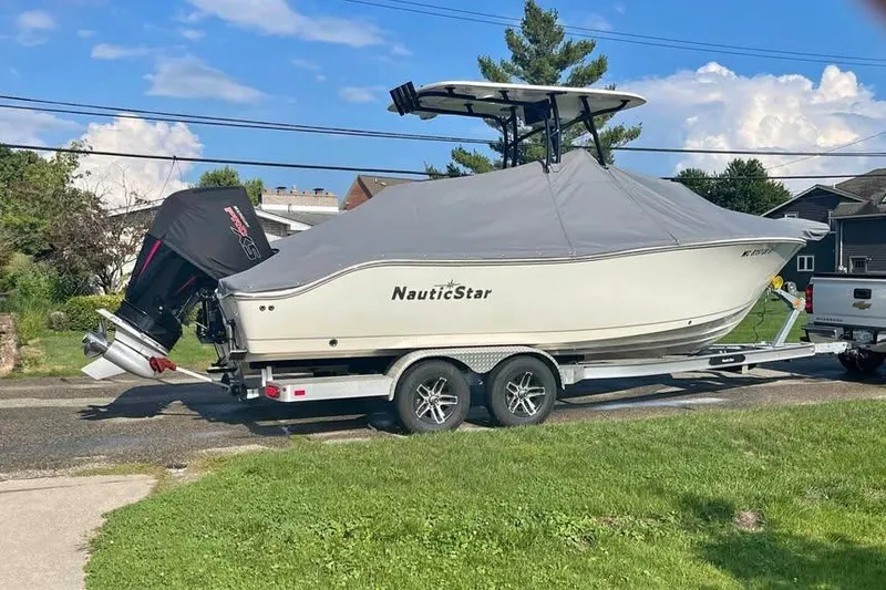 Slide: The Image of 2022 NauticStar 2302 Legacy boat on trailer, covered, parked outdoors. - 2