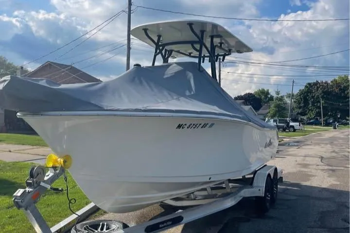 Slide: The Image of 2022 NauticStar 2302 Legacy boat on trailer, covered, parked on street. - 3